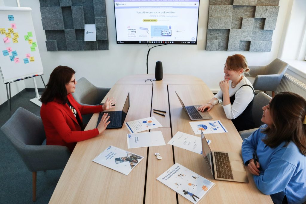 a group of people sitting around a table with laptops